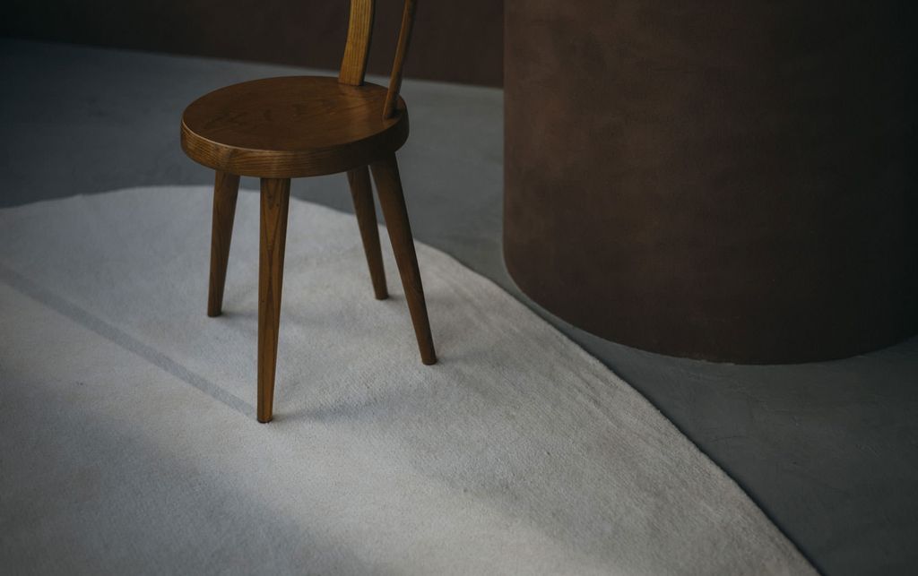 ひんやりとした印象の床に楕円でホワイトのWOOLRUGが置かれている