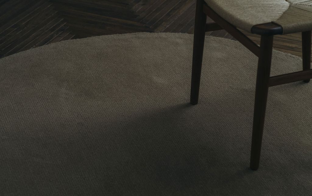 あたたかみのある床に楕円でベージュのWOOLRUGが置かれている